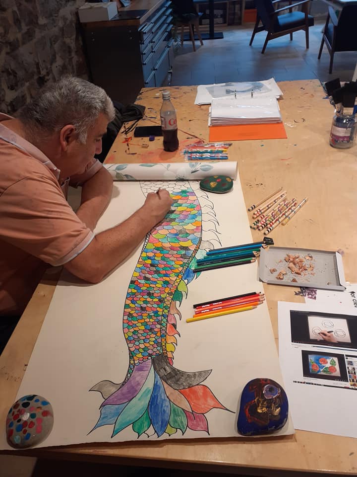 Man creating the colourful scales for a fish